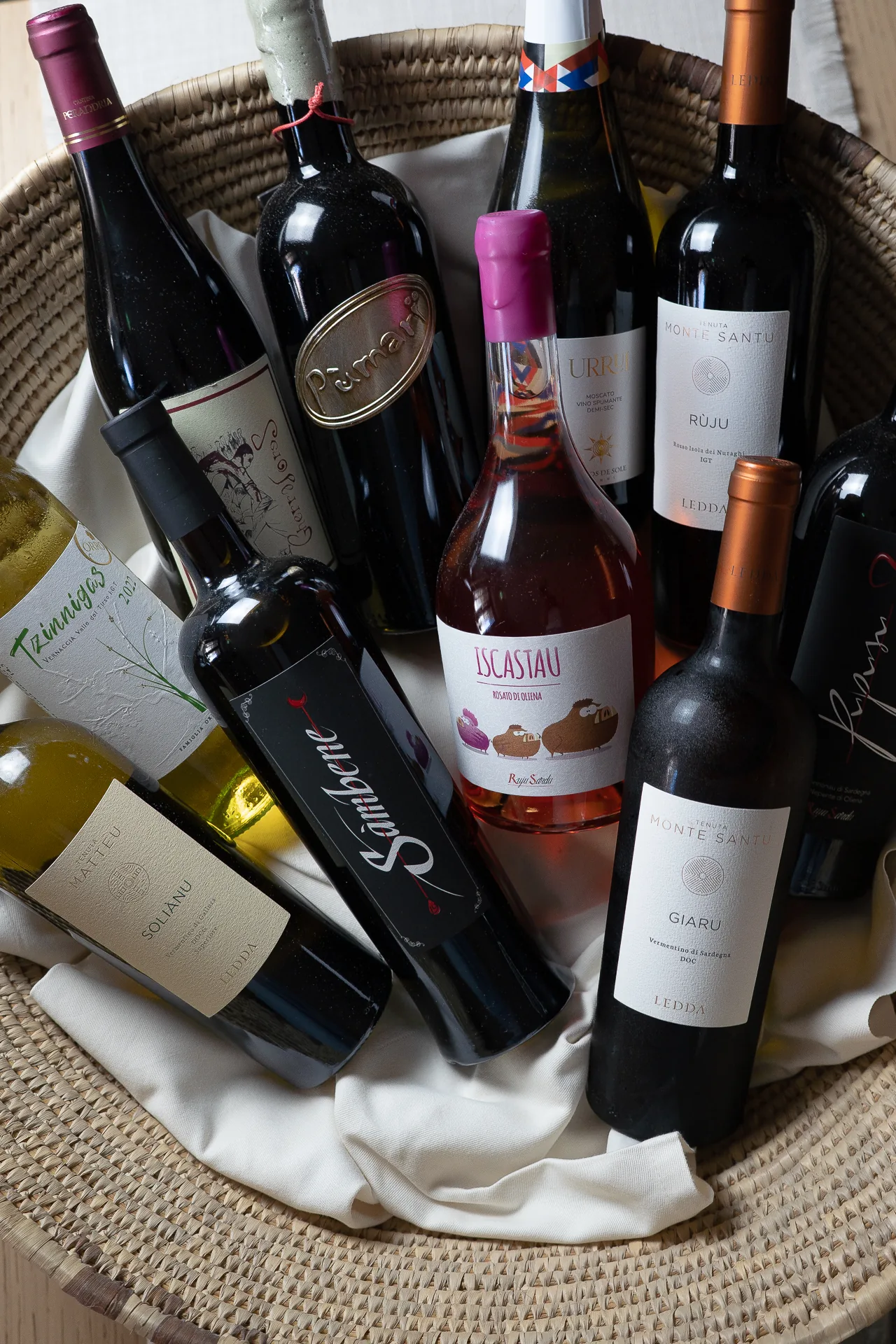 Bottiglie di vino assortite in un grande contenitore intrecciato.