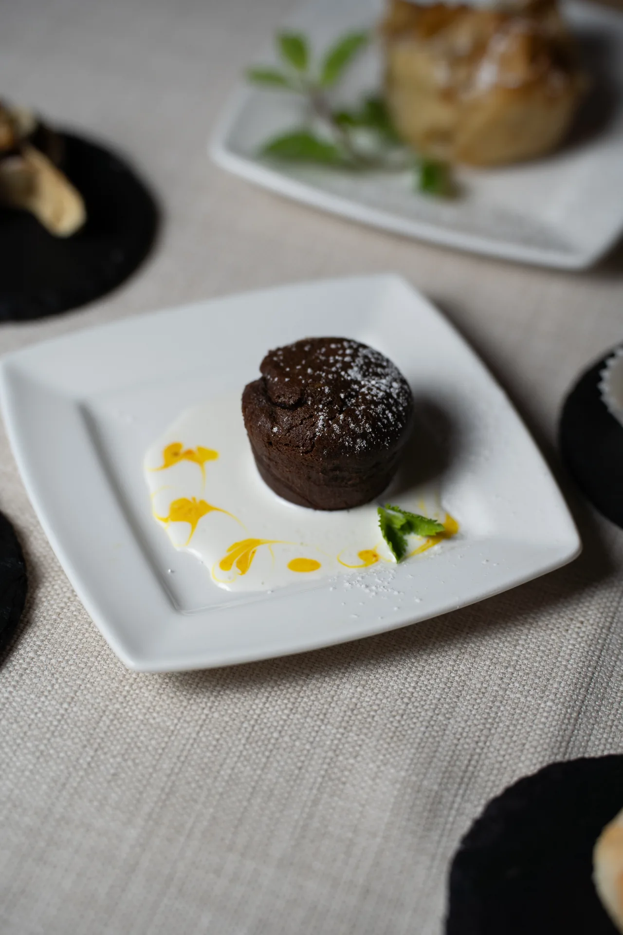 Tortino al cioccolato con zucchero a velo e salsa gialla.